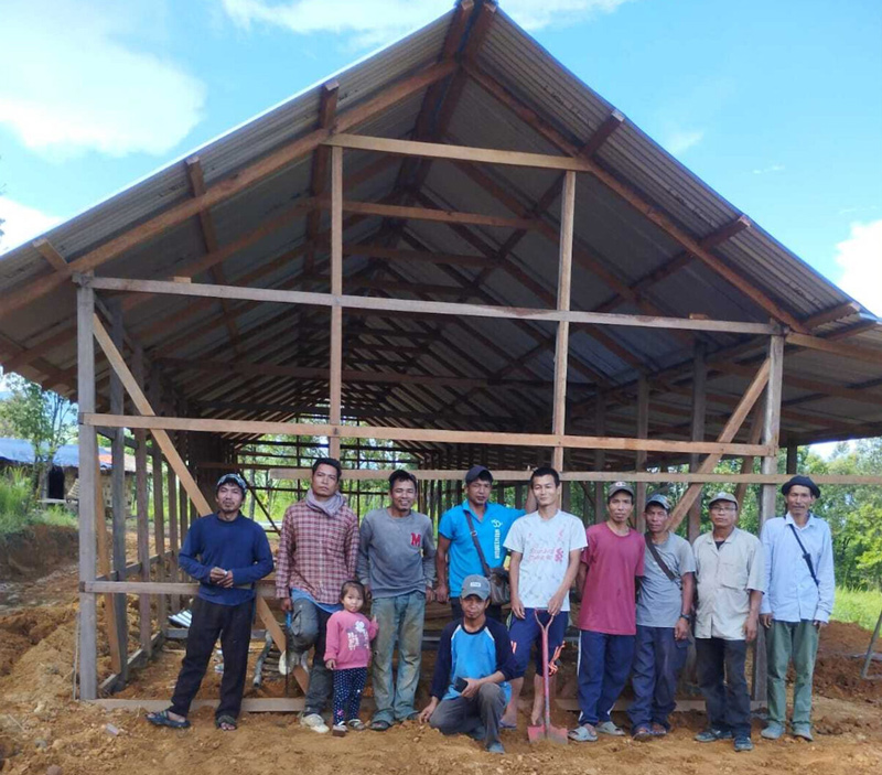Members of India’s Bnei Menashe community pose outside a structure under construction as a semi-permanent dwelling for nine families displaced by ethnic violence in the Manipur region of India. (Courtesy Degel Menashe)